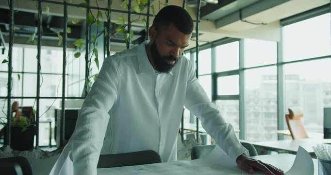 A professional in a modern office is meticulously analyzing various project plans for effectiveness