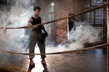 A woman in a boxing ring, holding boxing gloves in her hands, preparing for boxing training. The...