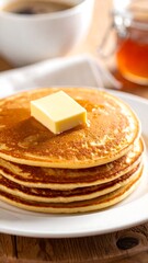 Stack of golden pancakes with butter and syrup