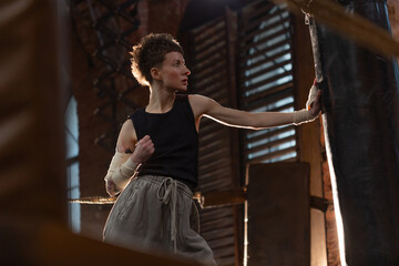 Female boxer training in cinematic gym lighting, powerful punch on bag with colorful dynamic lights