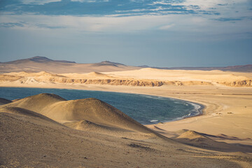 View of the arid desert landscape meeting the deep blue Pacific Ocean at Paracas National Reserve...