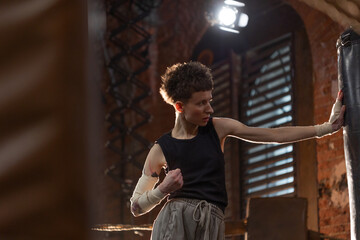 Short-haired boxer pausing workout, leaning on ring ropes with cinematic intensity