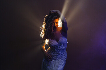 Cinematic shot of elegant dancer in white, illuminated by dramatic backlight in hazy setting