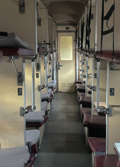Interior of an old Soviet-style sleeper train carriage with narrow corridor and open bunk beds. The...