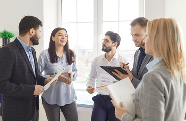 Positive business people handle documents and converse during office meeting or conference, strong...