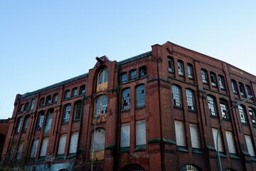 Obraz premium Altes Backsteingebäude mit zerbrochenen Fenstern und graffitierter Fassade bei blauem Himmel