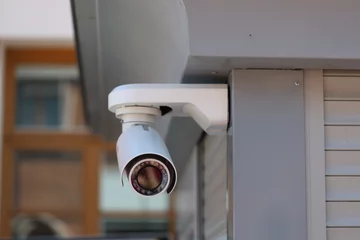Fototapete Rund Grau A security camera installed on the side of a building, providing surveillance and monitoring capabilities  © Fotograf