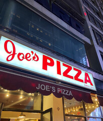 Naklejka premium New York City, USA, April 1, 2024: Joe's Pizza building façade in Greenwich Village, NYC. Established in 1975 by Joe Pozzuoli.