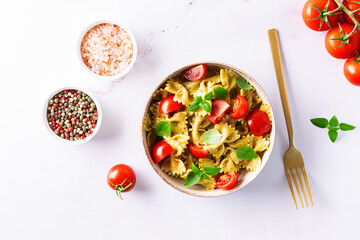 Aromatic homemade vegan farfalle with green pesto sauce, cherry tomatoes, basil leaves and homemade...