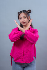 Confident young Indonesian Asian woman making an X sign with her arms to express rejection or...