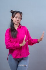 Asian Indonesian woman in a pink shirt making a stop gesture with both hands. She looks calm but...