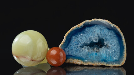 Processed semi-precious stones on a black mirror background.