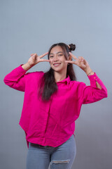 Happy young Indonesian woman with long hair and space buns hairstyle posing with double peace sign...