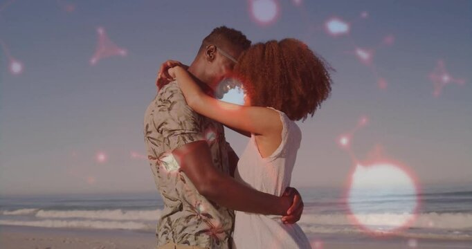 Wedding couple embracing on beach with sunlight sparking light hearts drifting around showing love