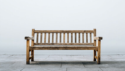 A weathered wooden park bench sits on a stone surface