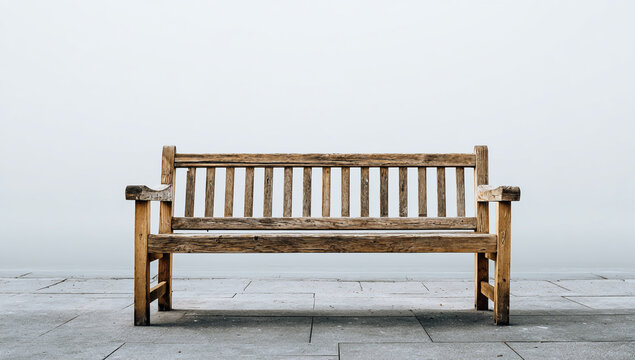 A weathered wooden park bench sits on a stone surface
