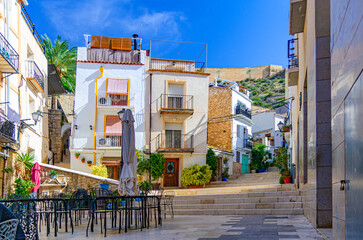 Alicante old town Santa Cruz neighborhood with Calle San Rafael narrow street steep stairs, typical white houses, street restaurant outdoor cafe in Alicante city centre, Valencian Community, Spain