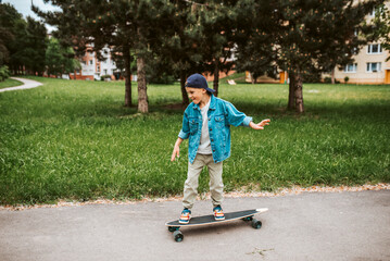 Young boy Learning to ride longboard on street.