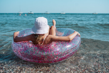 Girl on beach with swim ring during summer beach holiday.