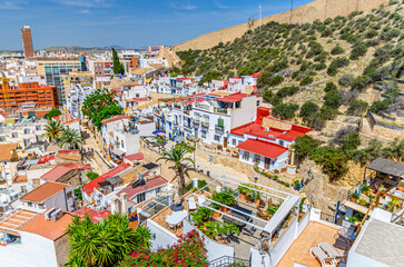 Aerial view of Alicante old town Barrio de Santa Cruz neighborhood narrow street, typical white houses, traditional colorful buildings in Alicante city historical centre, Valencian Community, Spain