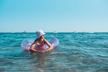 Girl on beach with swim ring during summer beach holiday.