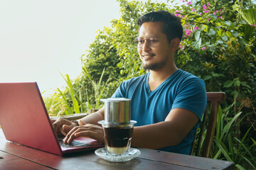 Man Working on Laptop Outdoors with Coffee in a Relaxing Environment