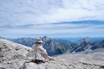 Steinmännchen auf felsigem Grat mit Blick auf Alpenpanorama und blauen Himmel