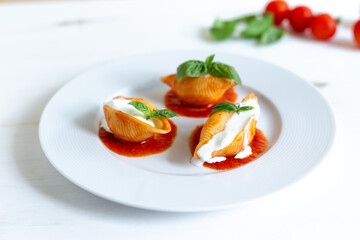 Traditional Italian Conchiglioni pasta with Italian Cheese, Tomato Sauce, and Basil Leaves