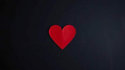 Minimalist red heart shape on a dark textured background, symbolizing emotion and warmth.