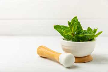 Fresh mint with mortar and pestle on wooden background. Melissa leaves. Healing herbs green mint...