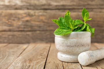 Fresh mint with mortar and pestle on wooden background. Melissa leaves. Healing herbs green mint...