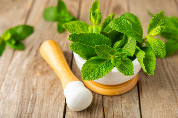 Fresh mint with mortar and pestle on wooden background. Melissa leaves. Healing herbs green mint...