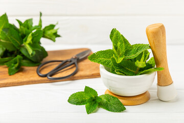 Fresh mint with mortar and pestle on wooden background. Melissa leaves. Healing herbs green mint...
