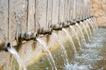 Water flowing from stone spouts in Brihuega, Guadalajara, during a sunny day in Castilla-La Mancha