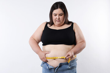 Overweight woman measuring her belly with tape on white background