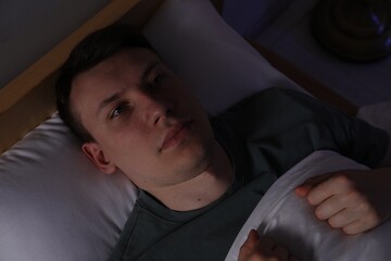 Frustrated man suffering from insomnia in bed indoors, top view