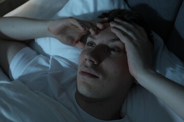 Frustrated man suffering from insomnia in bed indoors, above view