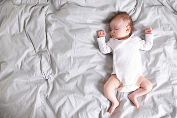 Cute newborn baby sleeping on bed, top view. Space for text