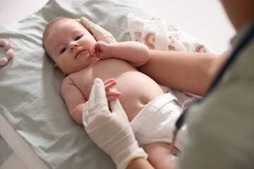 Pediatrician examining baby at table in clinic, closeup