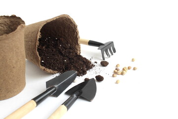 On a white background there are peat cups with soil.	