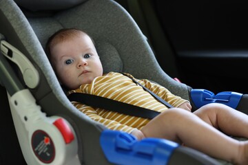 Cute little baby fastened in car seat