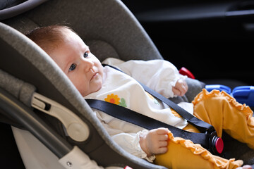 Cute little baby fastened in car seat