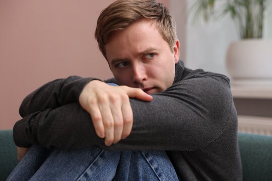 Scared man suffering from paranoia at home