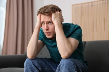 Man suffering from paranoia on sofa at home
