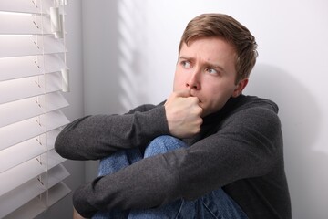 Man suffering from paranoia near window at home
