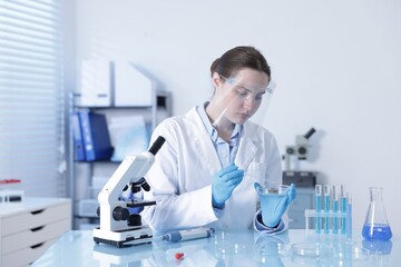 Scientist working with sample in Petri dish at table in laboratory