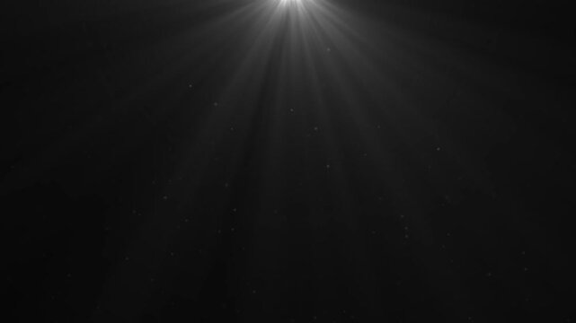 Seamless volumetric light from top in dark scene. White lamp rays shine on black background with floating backlit dust particles. Looped 3D animation in 4K for VFX overlays and design elements.