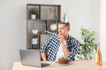 Happy man celebrating his birthday while having video call at desk indoors