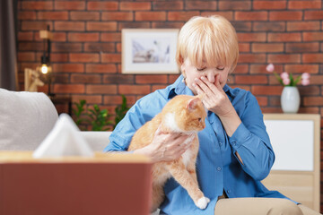 Senior woman suffering from allergy with her cat on sofa at home