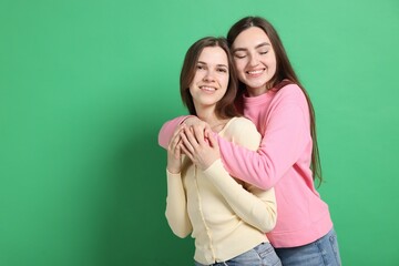Happy friends hugging each other on green background, space for text